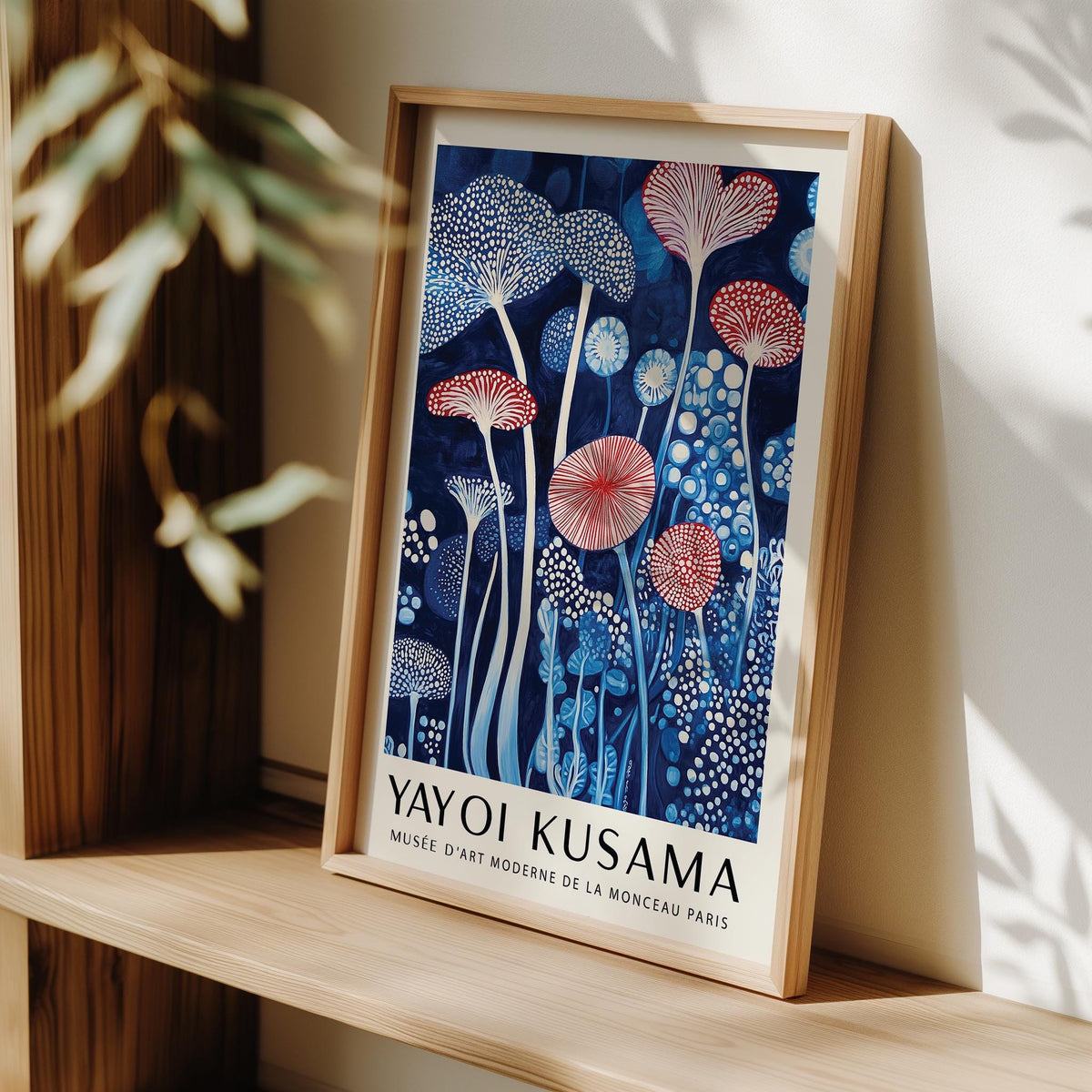 Framed Mushroom Art Print with abstract blue and red mushrooms leaning on a wooden shelf with leaves nearby