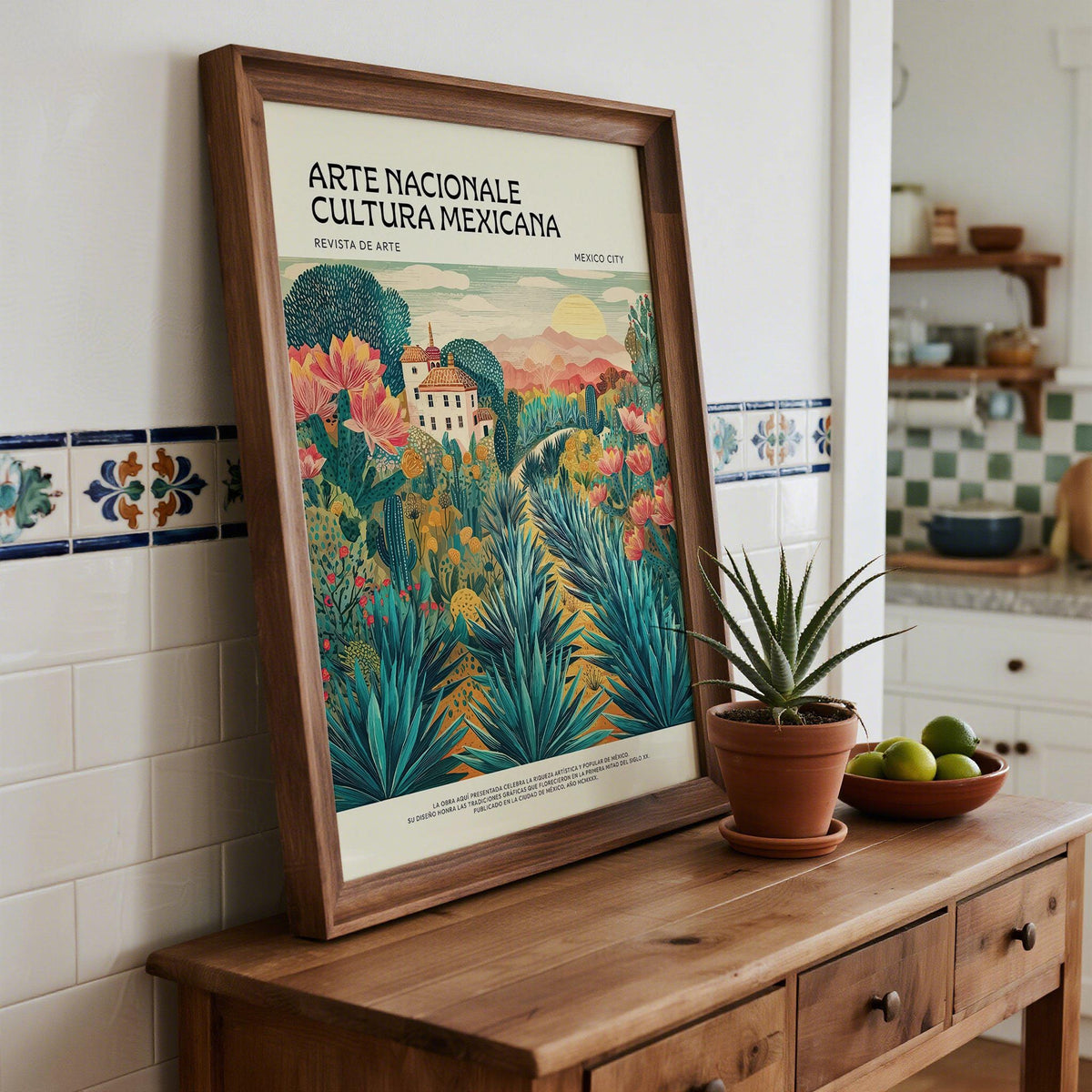 Framed Mexican Landscape Art print with agave plants and a house leaning on a wooden sideboard with plant pot