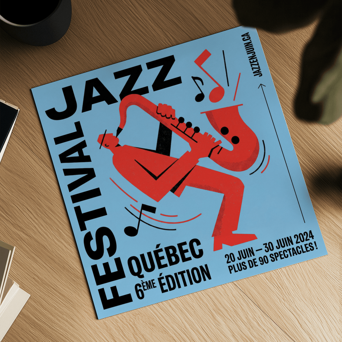 Top view of music wall art featuring a red saxophone player on a blue background on a wooden table with a black cup