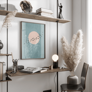 Wall Art Birds framed print with black birds in flight and a pink circle on blue background above a wooden desk