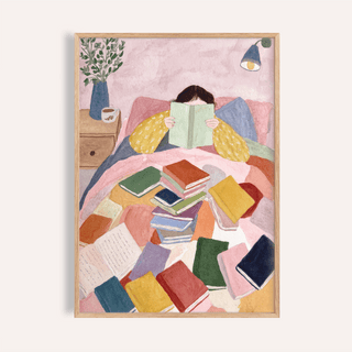 Framed print close-up of woman reading in bed art print with colourful books and soft pastels