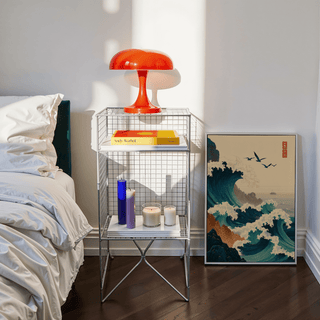 Print leaning on floor of Japanese wave art print showing ocean waves and birds next to a bedside table