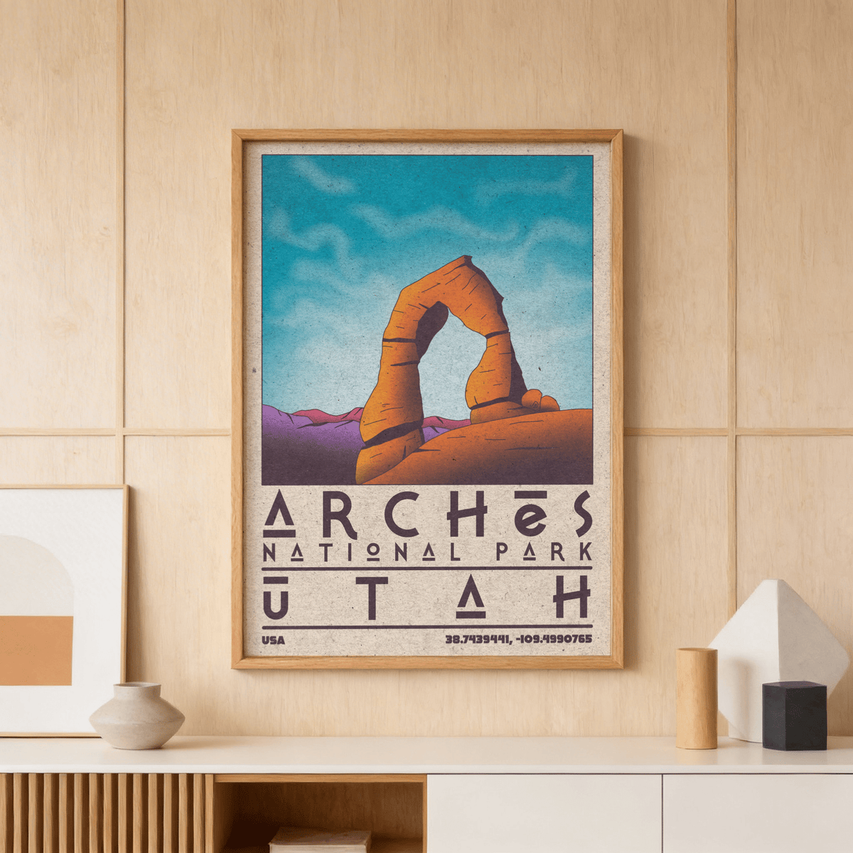 Utah wall art print on a wooden wall showing Delicate Arch with a bright blue sky and purple mountains above a shelf with ceramic vases