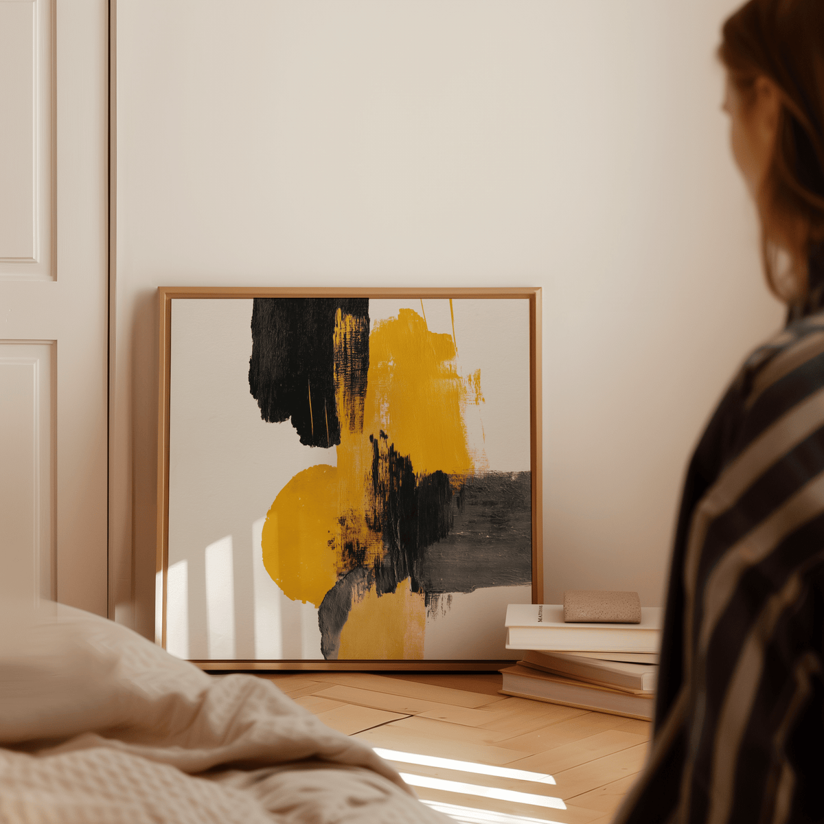 Abstract Square Art Print leaning on floor with black and yellow paint strokes and books nearby
