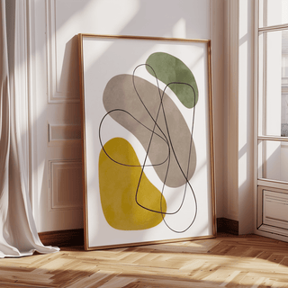 Print leaning on a floor with geometric abstract shapes in green mustard and taupe near a window