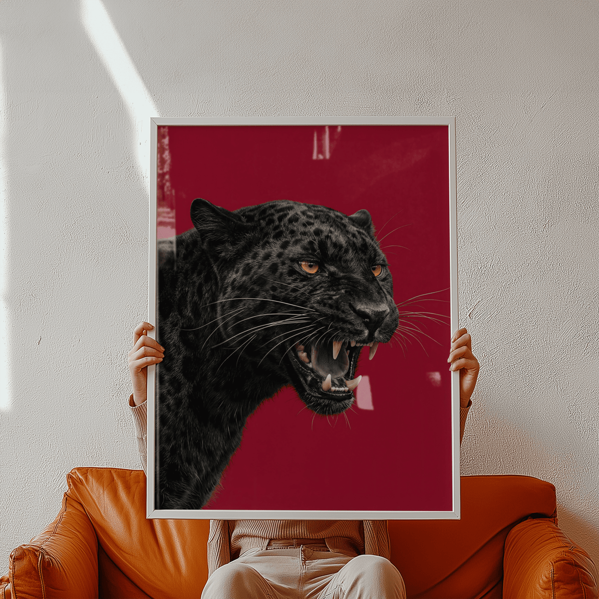 Framed black panther head photographic wildlife wall art with deep red background held on brown leather sofa