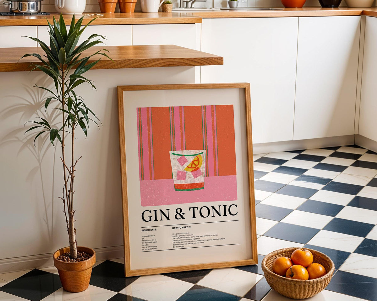 Kitchen art print of a gin and tonic cocktail with pink and orange stripes leaning against kitchen cabinets with a basket of oranges nearby