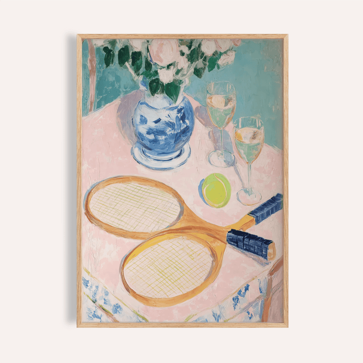 Framed print of tennis rackets with a ball and wine glasses on a pink tablecloth