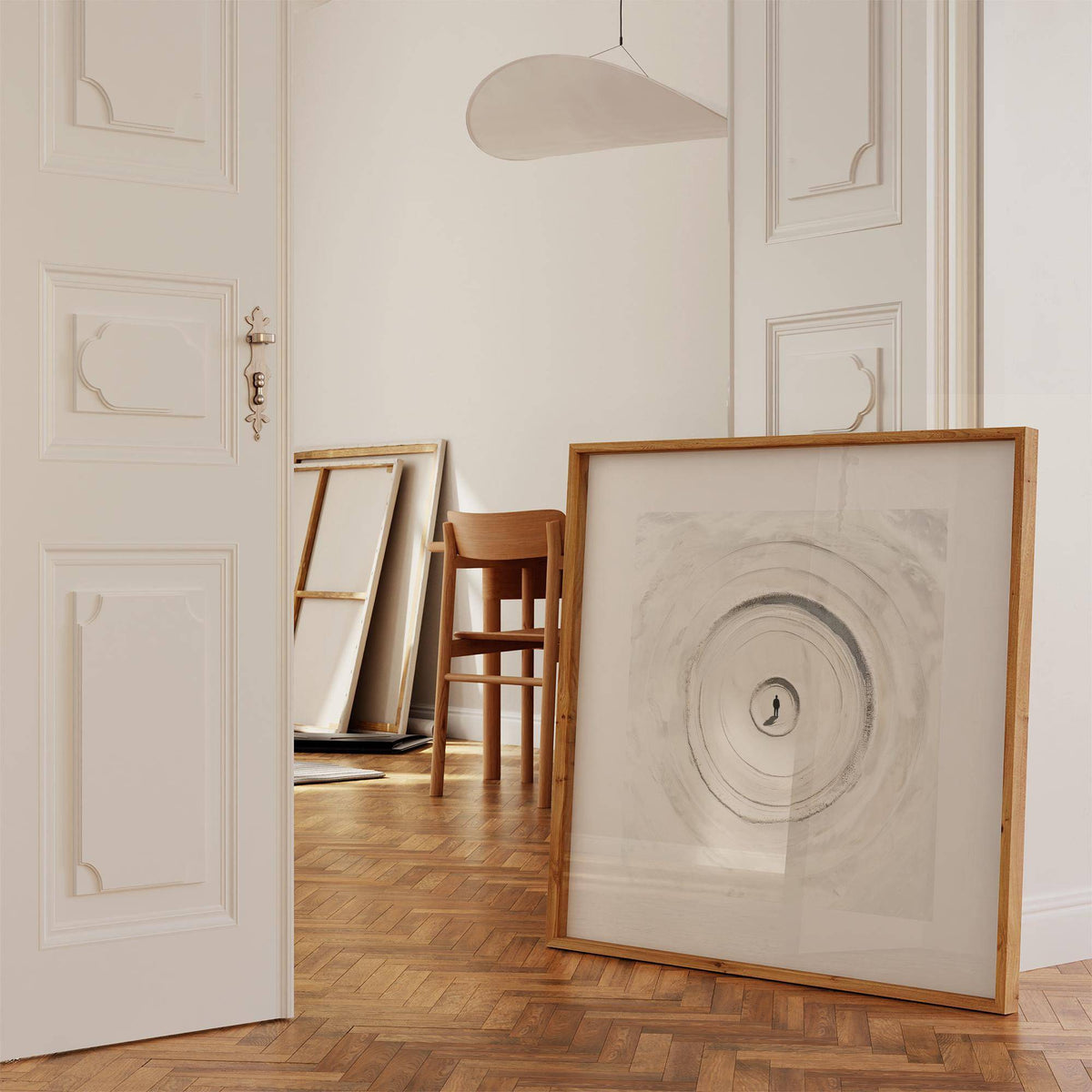 Print leaning on floor with concentric sand circle design in soft greys and neutrals against white wall