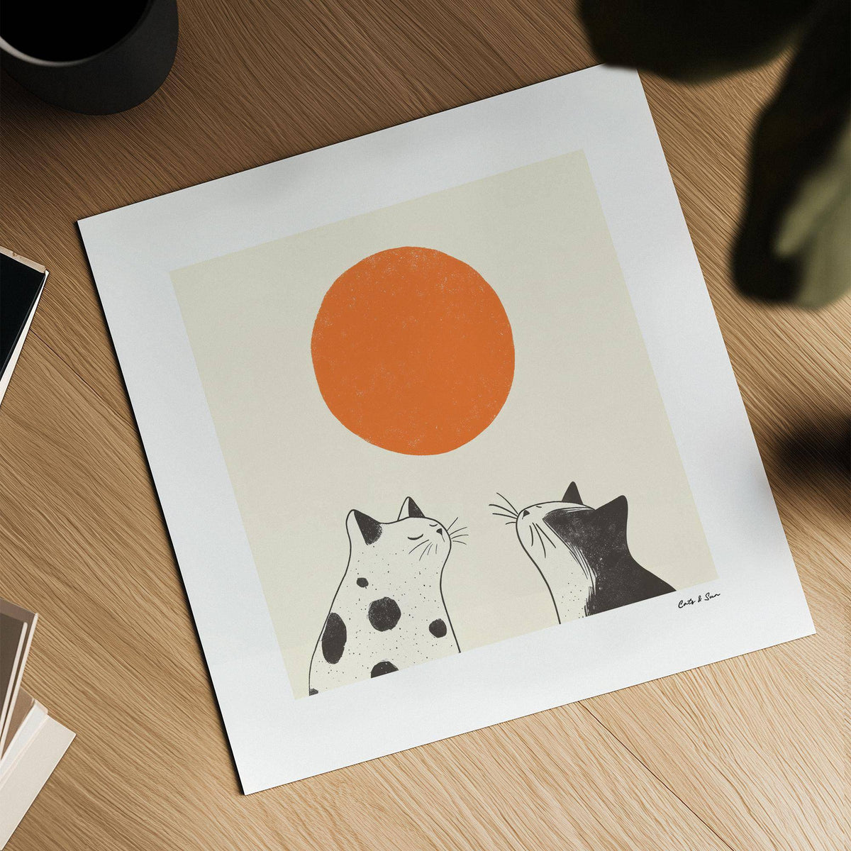 Orange Cat Art print of two black and white cats under an orange sun laid on a wooden surface