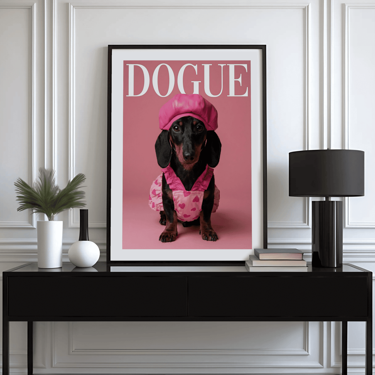 Fashion Dachshund wall art of a dog in pink outfit above a black sideboard with books and lamp