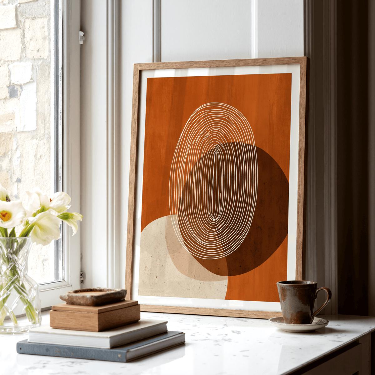 Modern Geometric Print leaning on a window ledge with a cup and flowers nearby