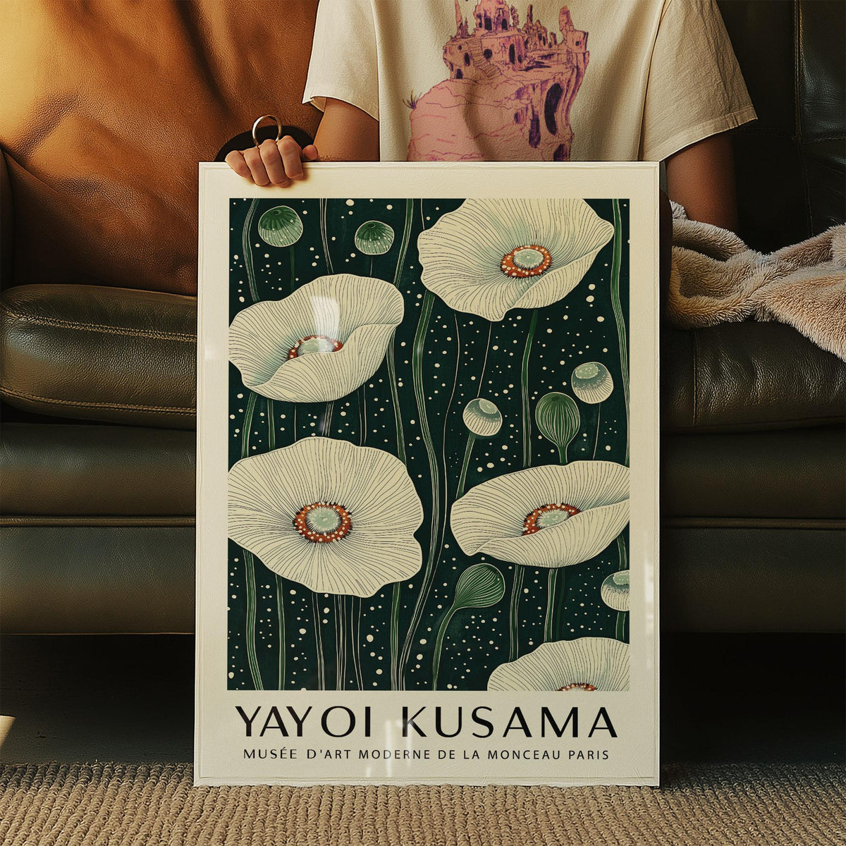 Framed Poppy wall art of white poppy flowers with green stems held by person on brown sofa