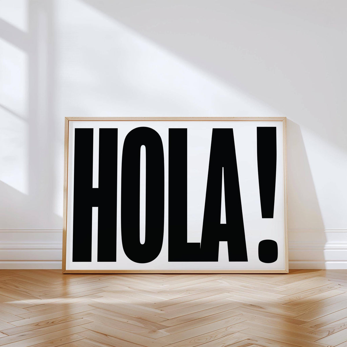 Typographic posters print leaning on a wooden floor with sunlight and shadows on a white wall