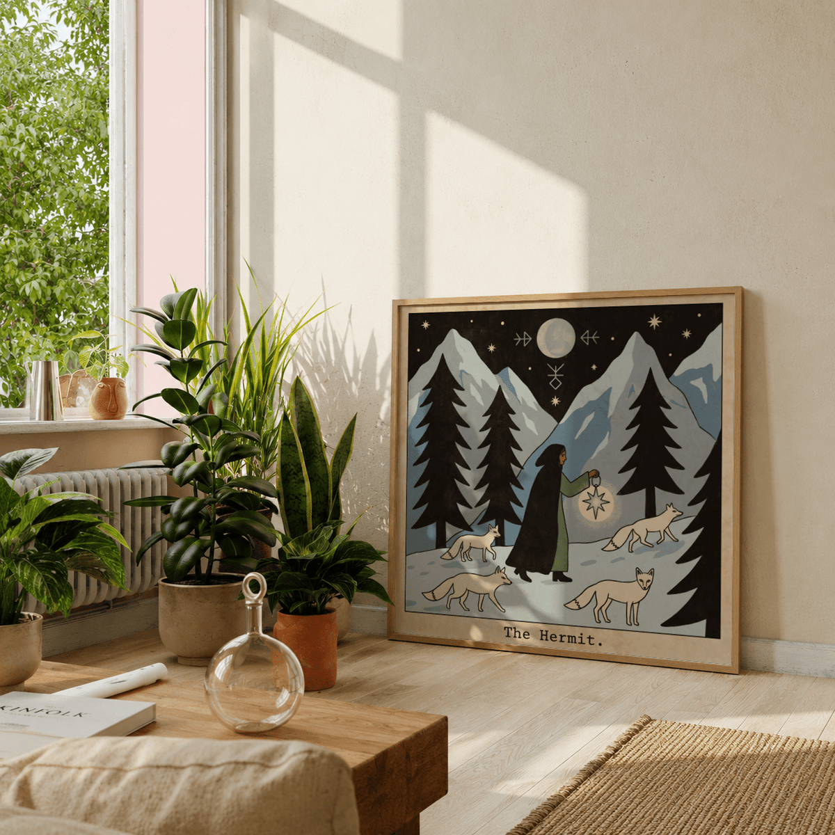 The Hermit Tarot Card Art print leaning on a light wall with green plants nearby in a bright room
