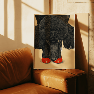 Poodle wall art leaning on a leather sofa showing a black poodle with red shoes in warm light