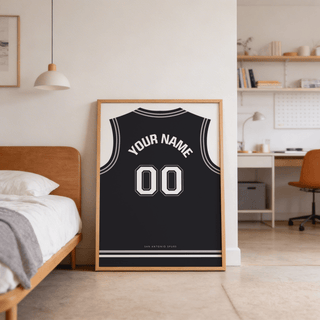 Print leaning on the floor of a black basketball jersey poster in black with white number beside a wooden bed