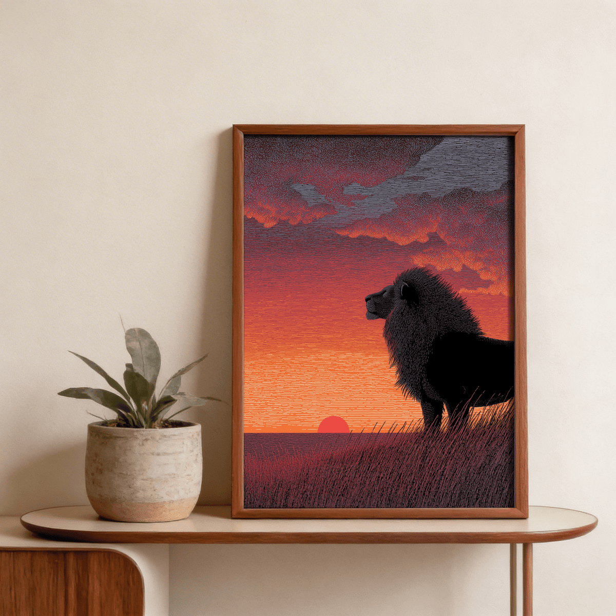 Framed Majestic Lion Art Print with black lion silhouette and vibrant orange sky displayed on a wooden table with a plant