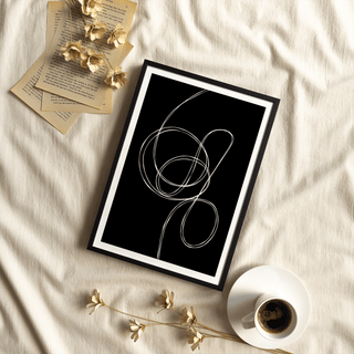 Modern Black And White Art framed print with white fluid lines on a black background near a cup of coffee