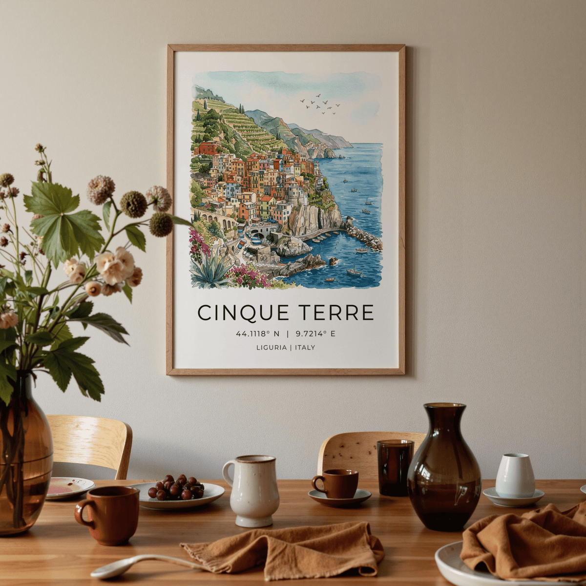 Cinque Terre art print of a colourful village coastline in watercolour framed above a dining table with crockery
