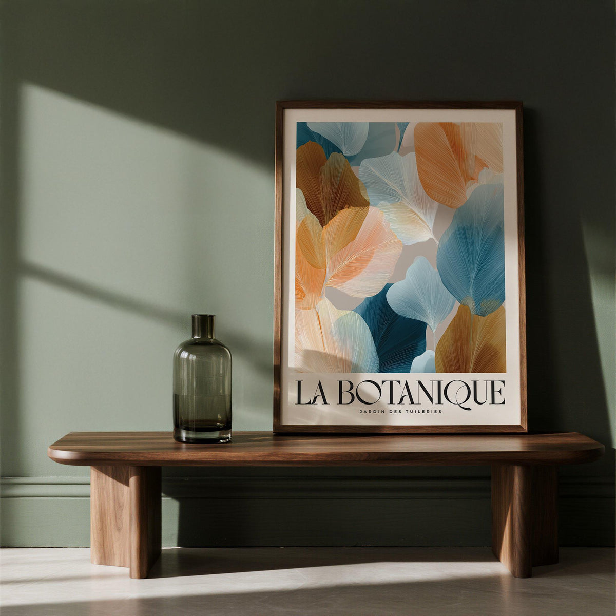 Flower art for walls leaning on a wooden bench with orange and blue botanical leaves and a glass bottle nearby
