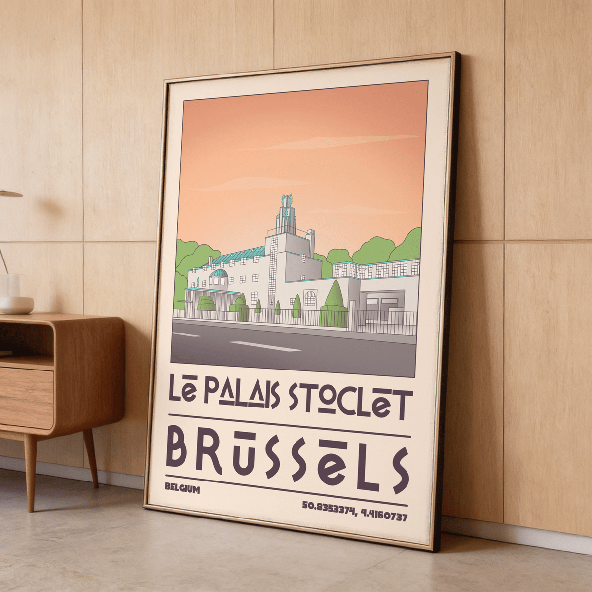 Art Deco Brussels Print leaning on wall with minimalist illustration in soft peach and green beside wooden cabinet