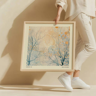 Framed minimalist poster art with abstract branches and dots in soft blue and gold held by a person in white