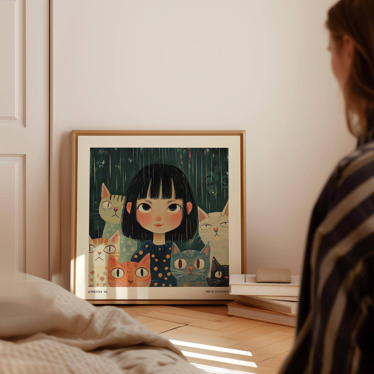 Print leaning on floor of girl with cats in moody blues and orange near stacked books