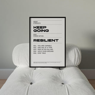 Keep Going Poster leaning on a white cushioned chair with black frame and minimalist typography