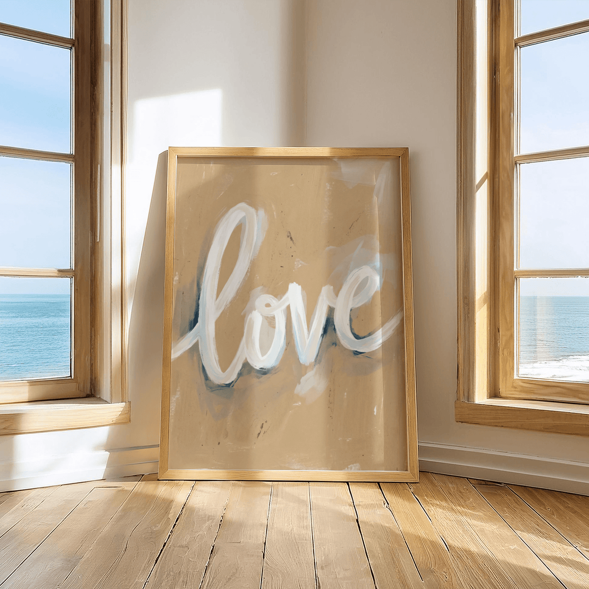 Love wall art print leaning on wooden floor between windows with sea view