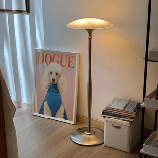 Dogue Poodle Print leaning on the floor next to a modern lamp and stack of books