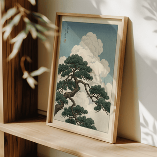 Japanese Landscape Poster leaning framed print of a pine tree branch against soft blue sky with white clouds on a wooden shelf