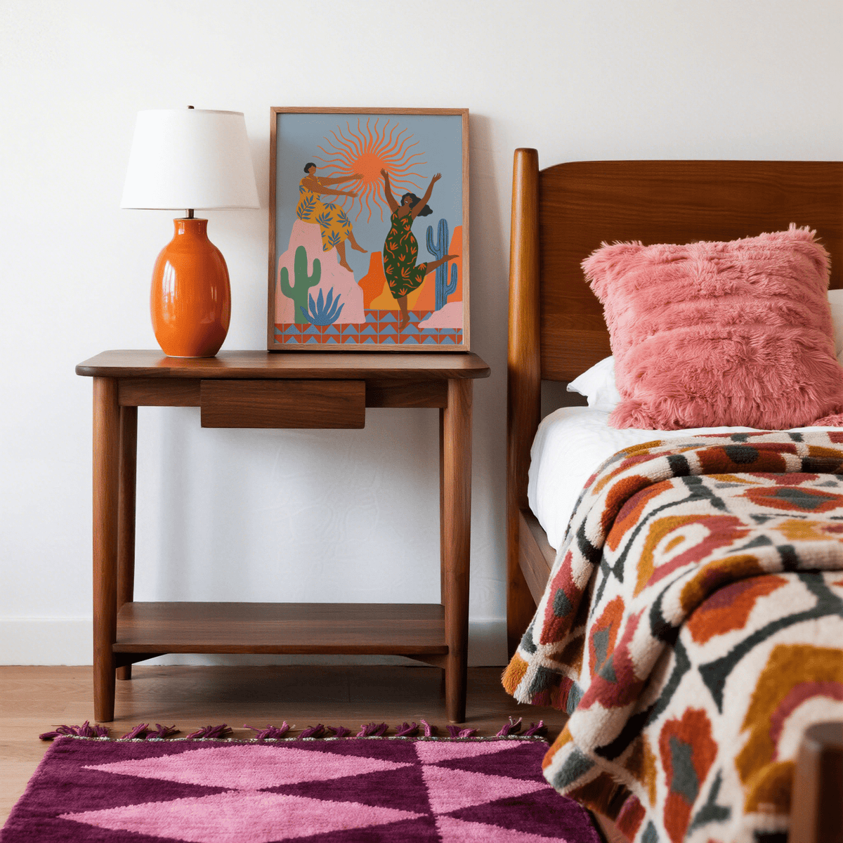 Sunset Women Art Print leaning on a wooden bedside table with an orange lamp in a bedroom