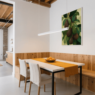 Print on a wall of hanging avocados in green and brown above a dining table with orange runner