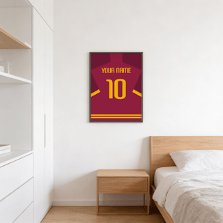 Football shirt poster in maroon with yellow number on a white wall above a wooden bedside table in a bedroom