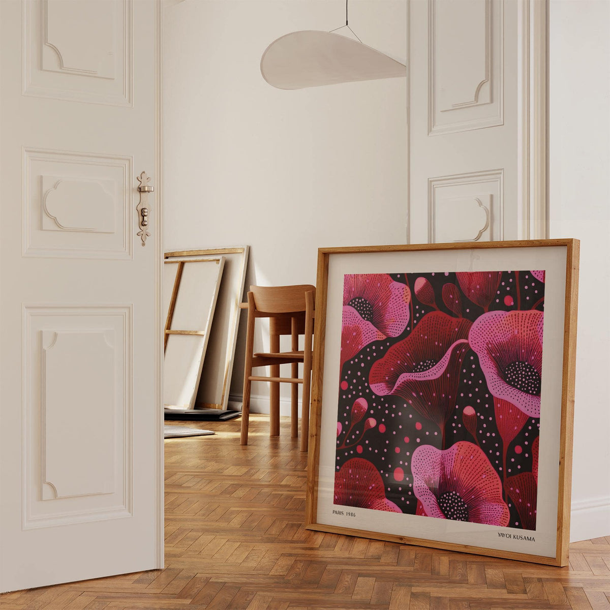 Print leaning on a parquet floor of abstract pink poppy flowers with black and dark red details in a doorway