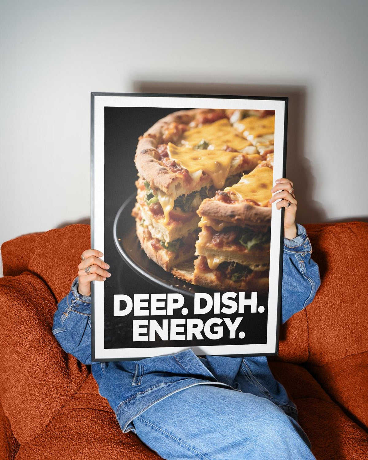 Framed Foodie Gift Idea print of deep dish pizza slice with melted cheese held on an orange sofa