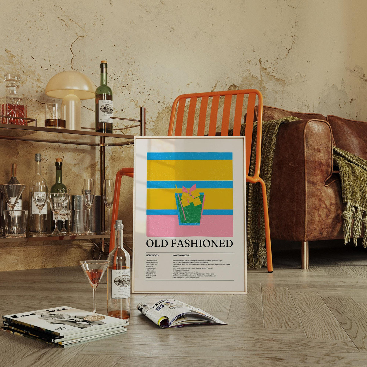 Drink Wall Art for Kitchen leaning on the floor with old fashioned cocktail illustration and bold colours near a book stack