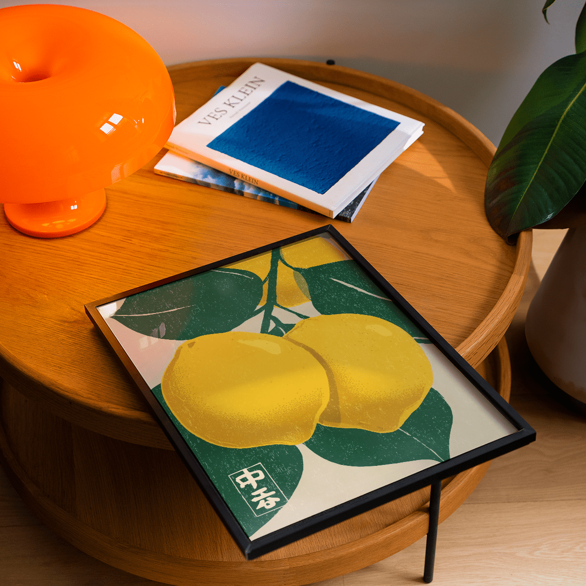 Framed Large Citrus Fruit Art Print of two yellow lemons with green leaves on a wooden table with an orange lamp