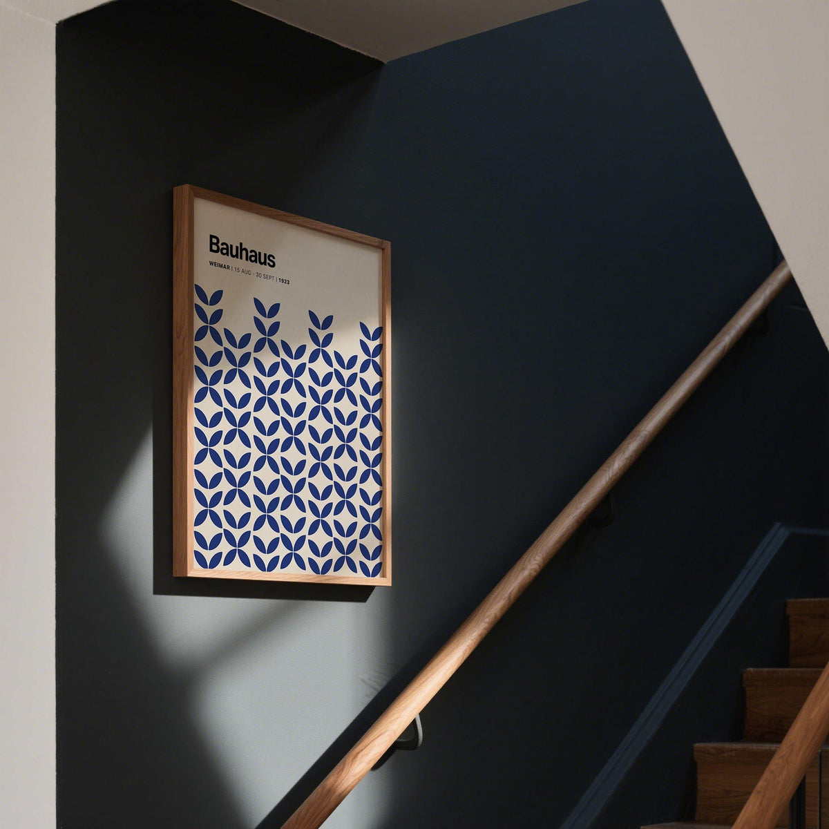 Simple Wall Art framed print with blue geometric pattern on a dark blue stairway wall with wooden handrail