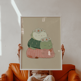 Framed Cute Cat Art Print with stacked cats in white green and pink with daisies held by person above a brown sofa
