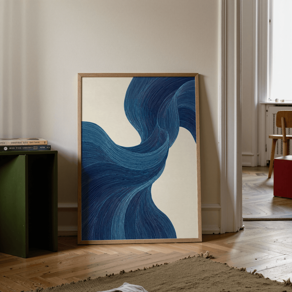 Print leaning on floor with blue flowing lines on cream background and green side table nearby
