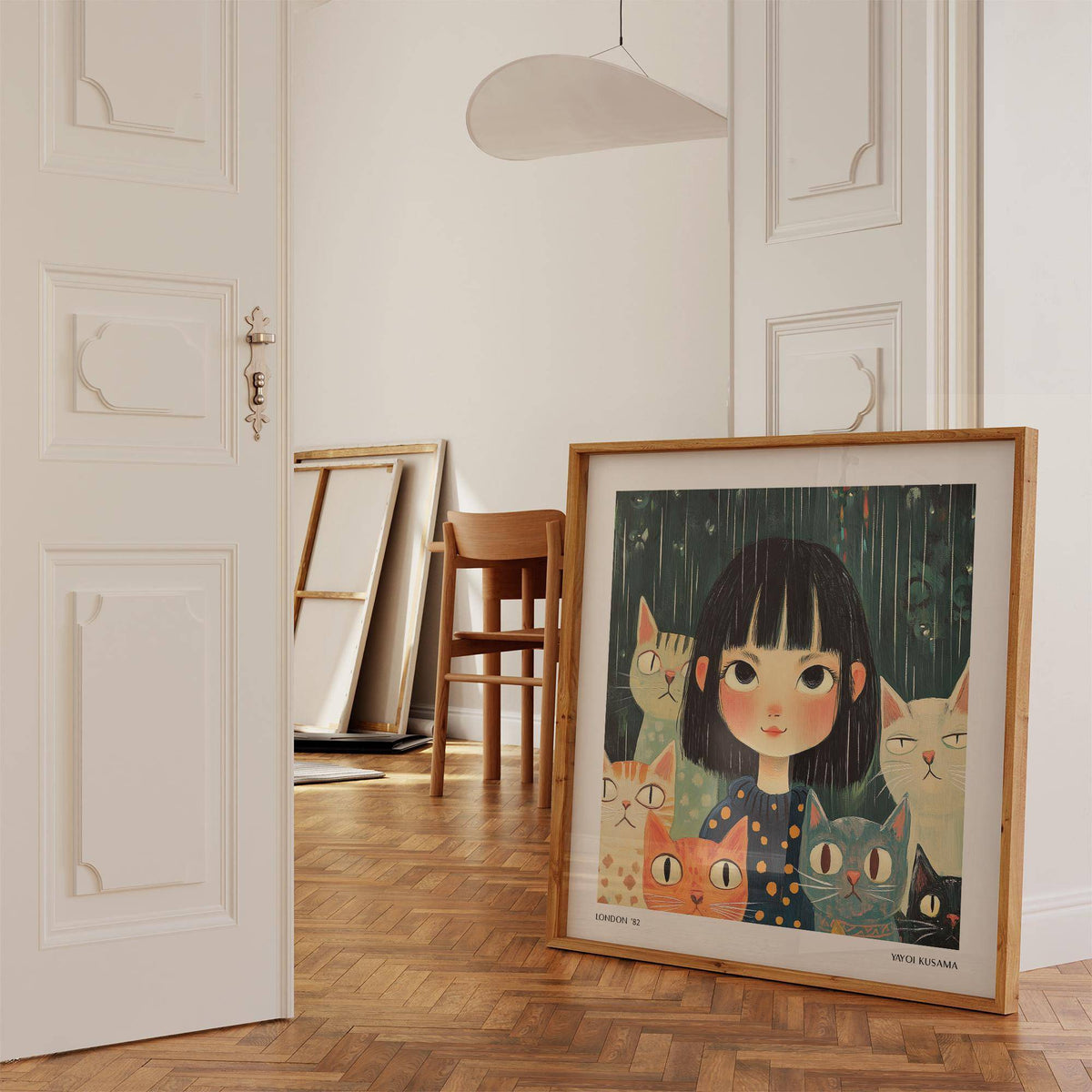Print leaning on wooden floor of girl with cats in dark blue and green tones near a wooden chair