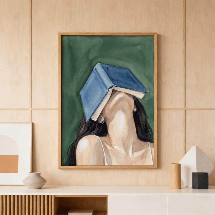 Woman Reading Portrait Print framed print of a woman with a blue book over her face in a beige room with decorative vases