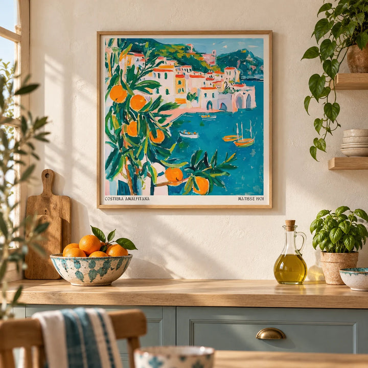Amalfi Coast Print, framed on the wall of a sunny Mediterranean-style kitchen with a warm white plaster wall and a pale oak worktop