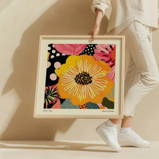 Framed Flower Posters showing a yellow flower with white petals and pink floral patterns held by a person