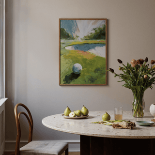 Golf Landscape wall art with a white golf ball and grassy fairway above a dining table with pears and a vase of flowers