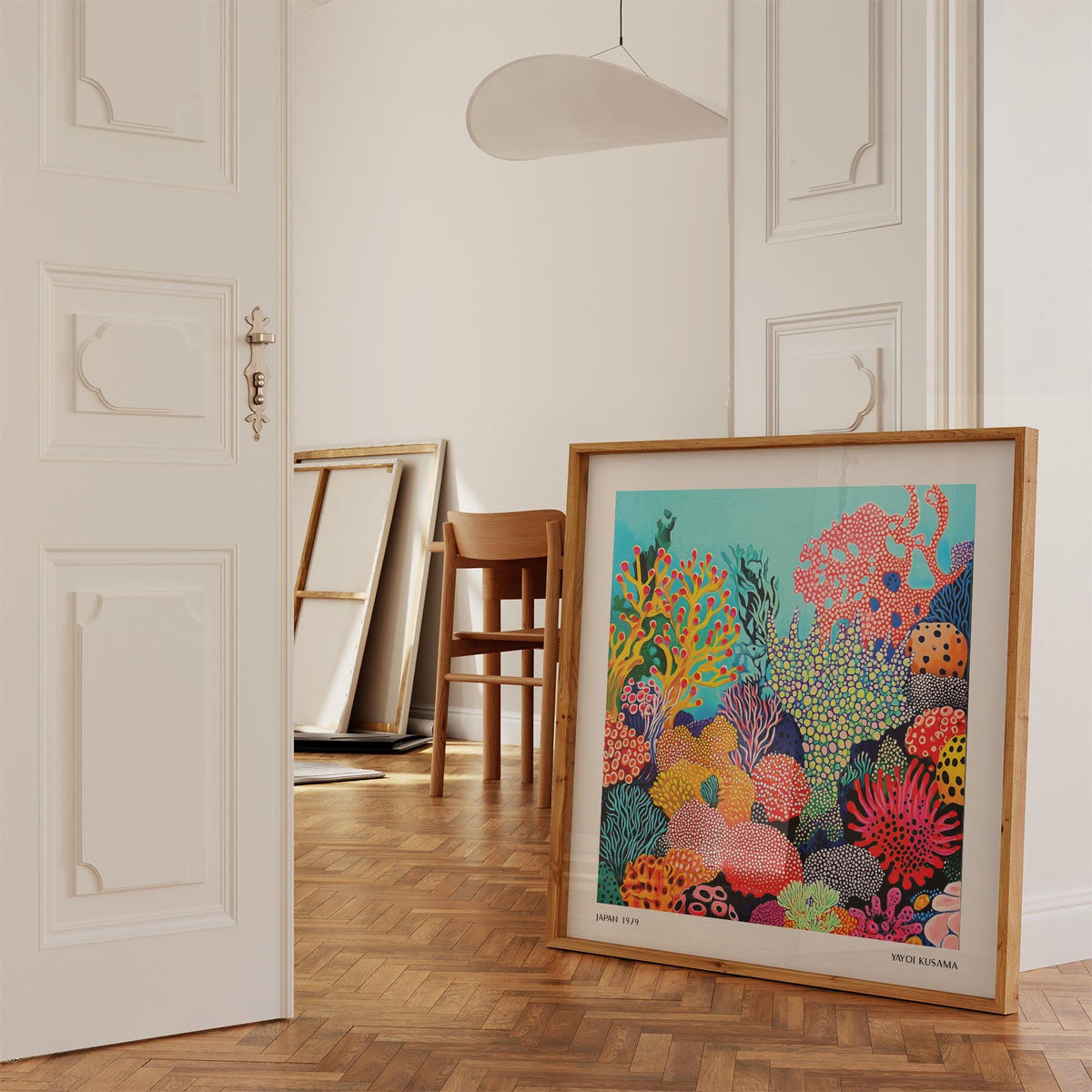Print leaning on floor of tropical sea wall art with colourful coral reef scene and wooden chair nearby