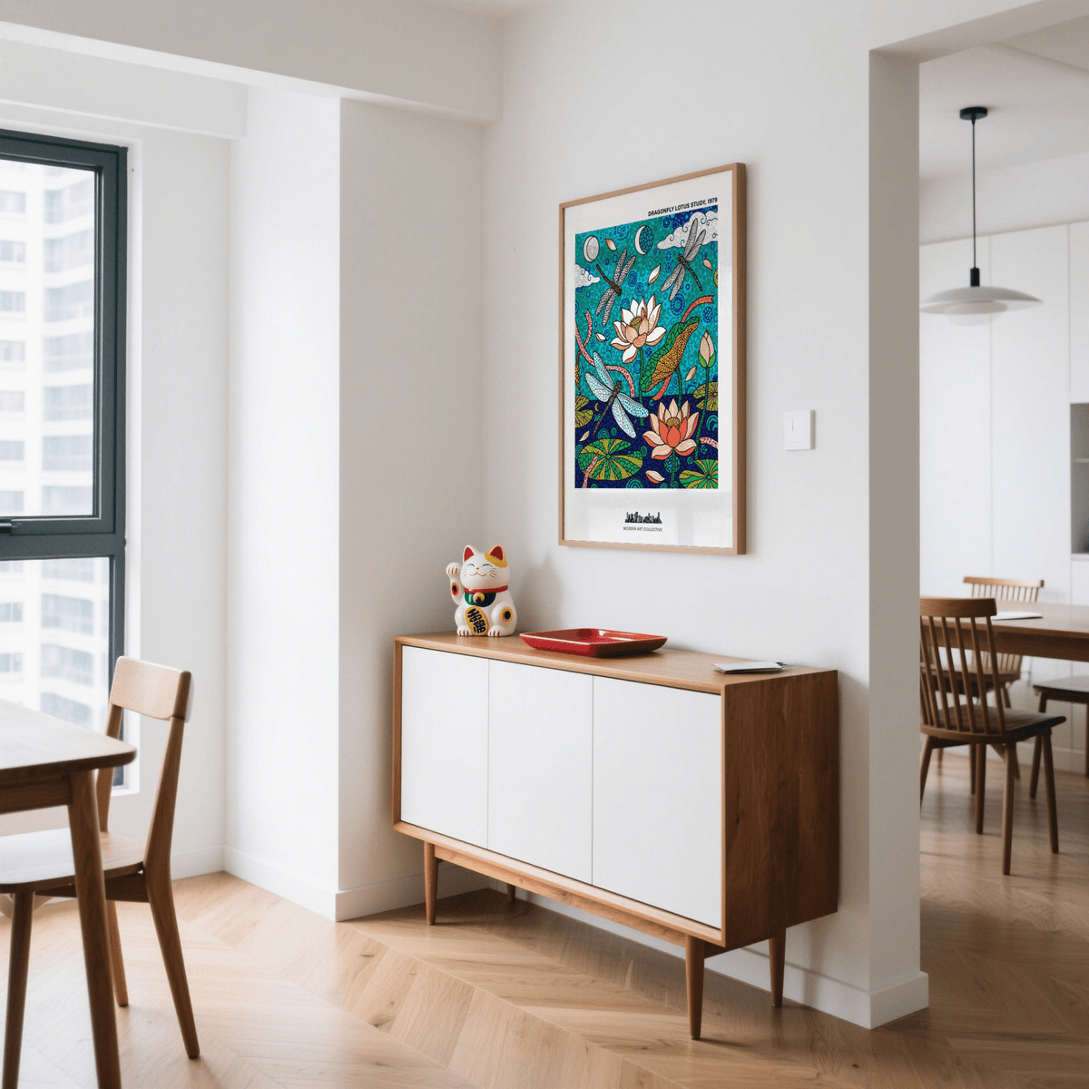 Dragonfly Lotus Art Print on a white wall above a wooden sideboard with a decorative cat figure in a dining area