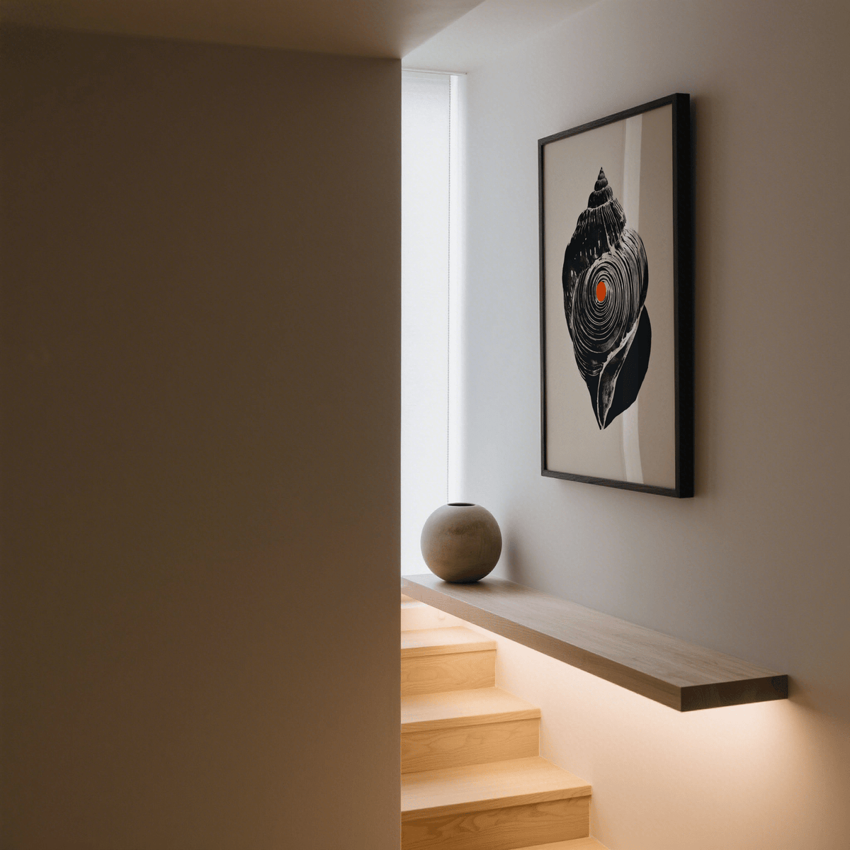Shankha art print of a black sea shell with orange dot on a beige background in a minimal stairwell with a round stone vase